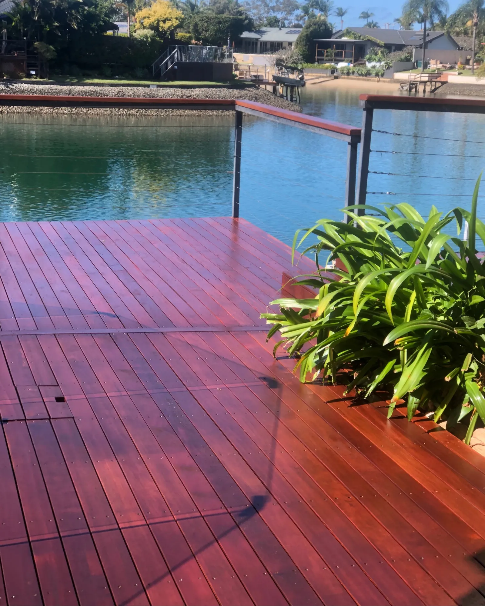 Restored mahogany hardwood deck with cable-rail balustrade overlooking a Gold Coast canal
