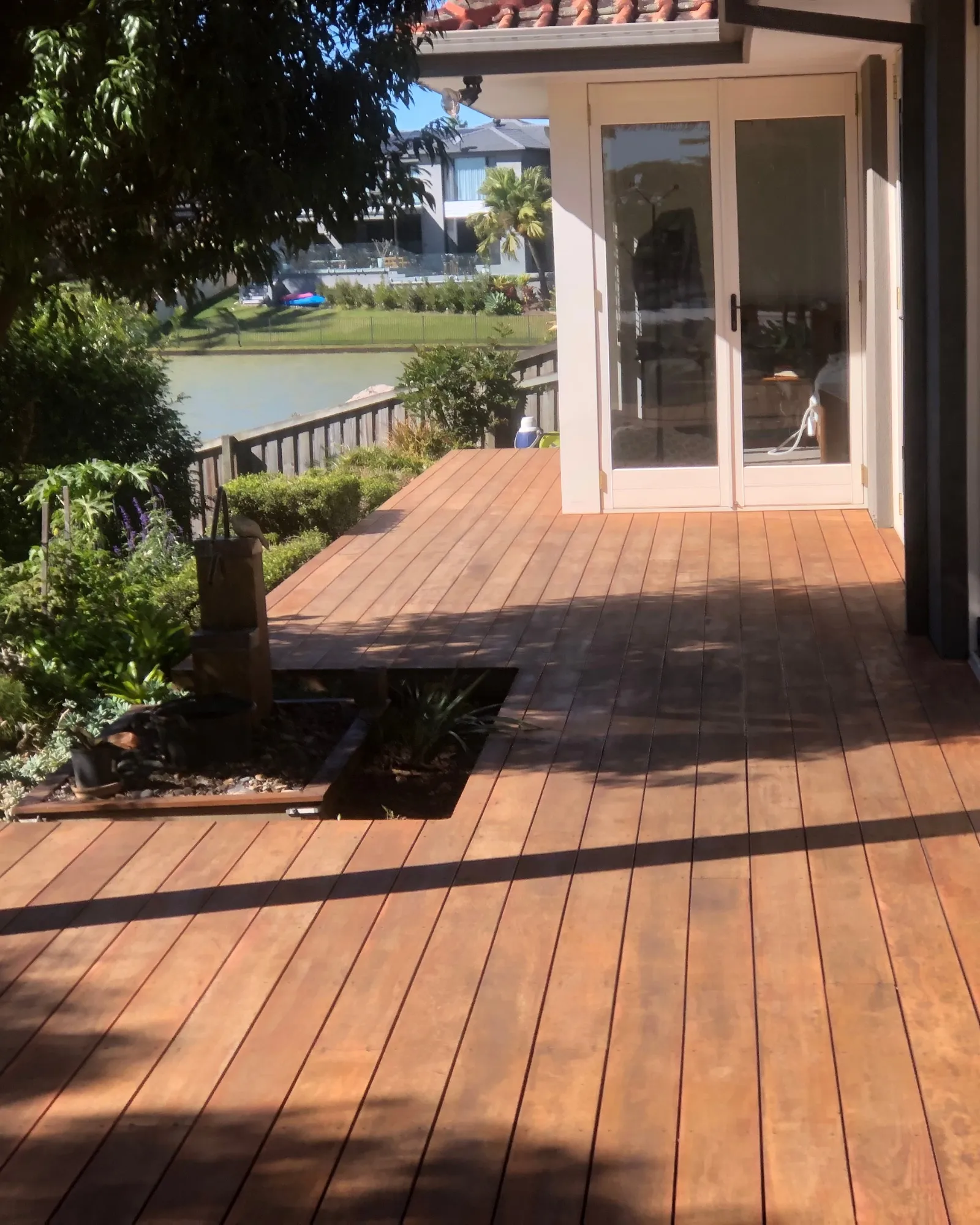 Hardwood waterfront deck wrapping a Gold Coast home with French-door access and canal views